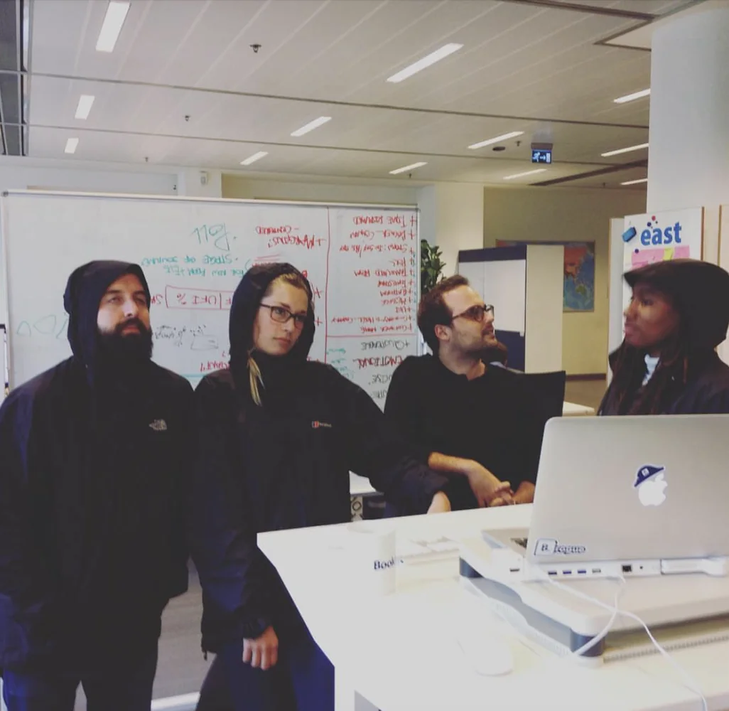 Tess and colleagues gathered around a laptop in front of a whiteboard full of notes